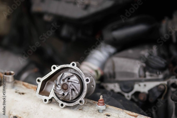 Fototapeta concept of replacing the water pump of the car engine cooling system, a new aluminum car spare part pump.