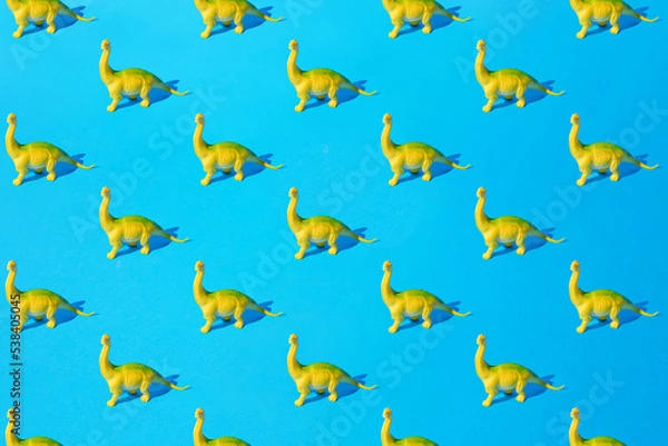 Fototapeta Yellow green plastic toy Brachiosaurus dinosaur on a blue background. Minimal pattern.