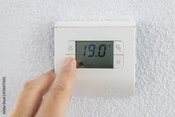 Obraz Thermostat is manually lowered to a temperature of 19 degrees Celsius.
