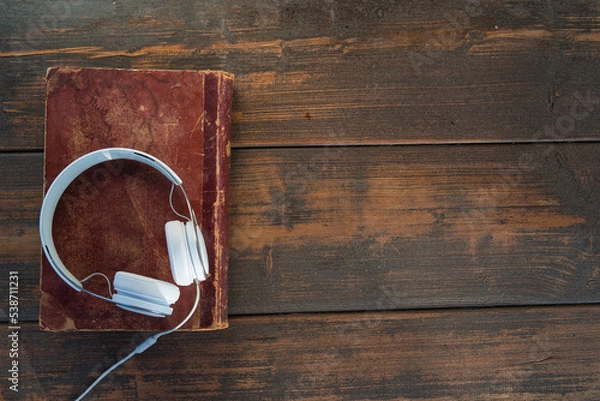 Obraz headphones on old book and wooden background