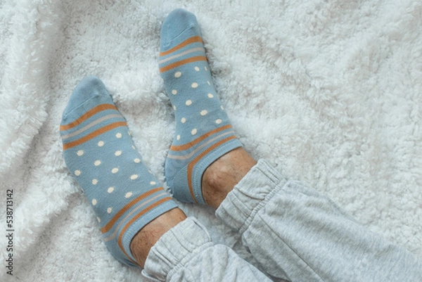 Obraz Women's legs in socks on a white fluffy plaid, at home in a cozy autumn season. Rest at home after a hard day's work. Varicose veins on legs. Swollen legs, problems with the bone in the legs.