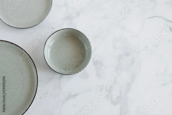 Fototapeta Empty ceramic plates and bowls top view on white marble  background with copy space. Flat lay natural color plates brending template. Food concepte.