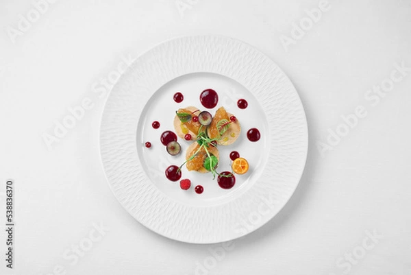 Fototapeta Foie gras with apple confit and berry sauce in a white plate on a white background. Close-up, selective focus.