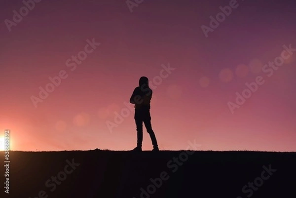 Fototapeta man trekking in the mountain with a sunset background in summertime