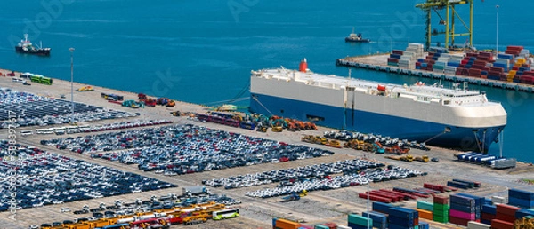 Obraz Lined up imported cars with car carrier ship anchored at the terminal.