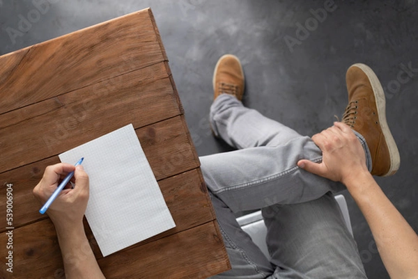 Fototapeta Man writing on notebook at table thinking idea solution. Study or design creative concept