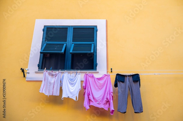 Obraz drying clothes on an old window against a yellow wall