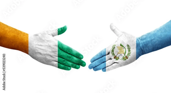 Fototapeta Handshake between Guatemala and Ivory Coast flags painted on hands, isolated transparent image.