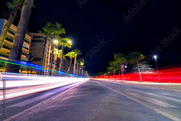 Fototapeta Long exposure with vehicle light streaks at night on the harbor by the sea in Vloe, Albania
