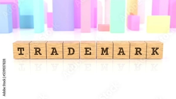 Fototapeta Word with the text TRADEMARK chiselled on wooden blocks reflected on the white table. Business concept. In the back are colorful cuboids in different shapes. (3D rendering)