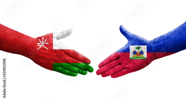 Fototapeta Handshake between Haiti and Oman flags painted on hands, isolated transparent image.