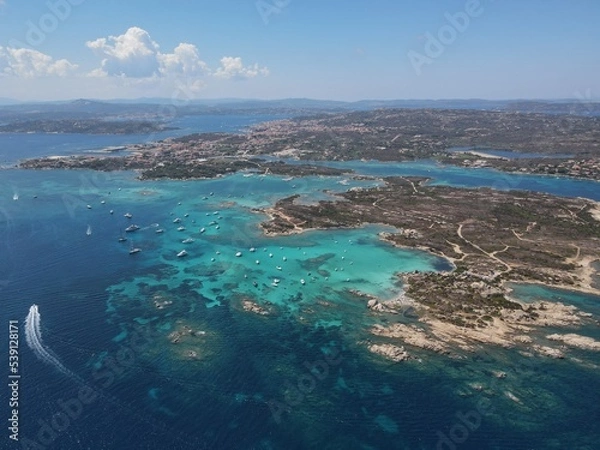 Fototapeta Aerial view of La Maddalena Island, Isola Giardinelli with the drone view of Caprera Island in Sardegna, Italy. Birds eye view of crystalline and turquoise water in north Sardinia, luxury yacht, boat.