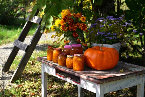 Fototapeta Vintage still life with jars of pumkin jam and fall flowers on the old table in the garden outside