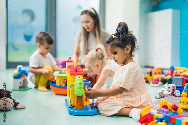 Fototapeta preschoolers building with toys and cubes and enjoying in kindergarten with teacher, creative activities for kids. High quality photo