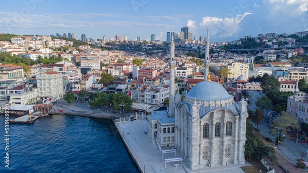 Fototapeta Skyscrapers of istanbul behind Ortaköy Camii mosque and city behind, aerial view of the Bosporous in Istanbul
