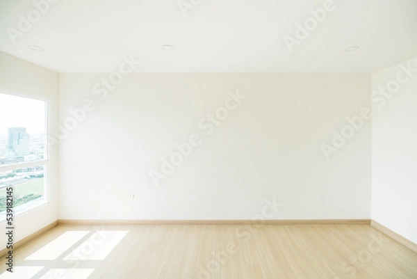 Fototapeta Empty room is decorated with an engineering wooden floor and wallpaper on the wall with sunlight from the window. Minimalist interior design and real estate for decoration. Real image with copy space.