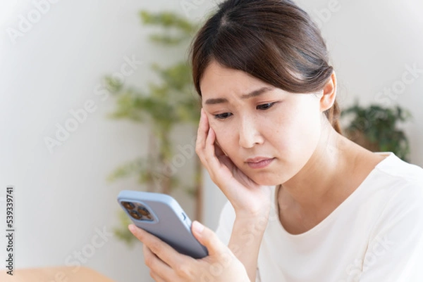 Obraz スマホを見て落ち込む女性