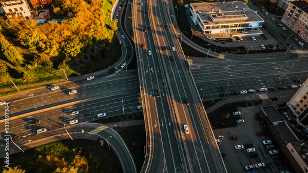 Fototapeta Heavy traffic car junction. Drone shot at a highway. A wide highway in the middle of the city at sunset. 