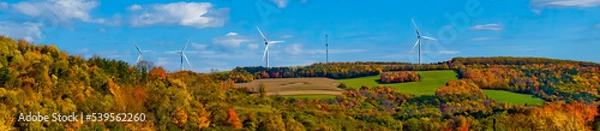 Obraz Windmill Turbines line the mountaintop ridge in central NY state.  Trying to offset CO2 emissions with wind farms.  Climate Change is forcing alternative power.  Autumn Leaves and Windmills.