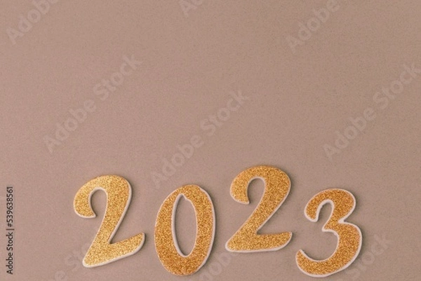 Fototapeta Numbers 2023 in golden color on a beige background. Upcoming new year, copy space