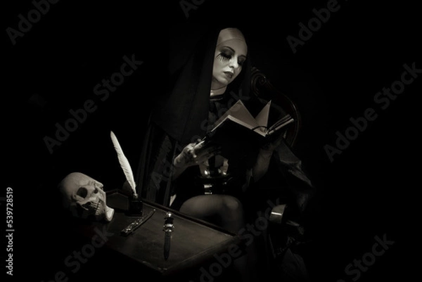Obraz A nun, in typical black and white clothes, writes in a notebook with a pen, sitting in an armchair