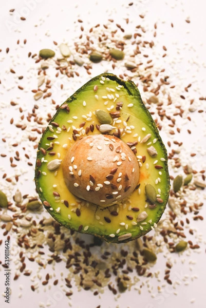 Fototapeta Close-up photo of a cut avocado on a white background sprinkled with grains.