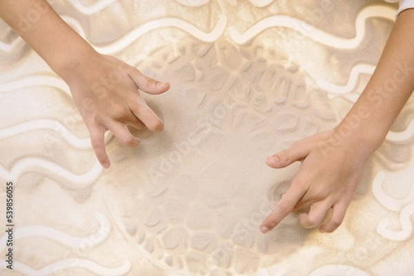 Fototapeta The child draws with fingers on the light table with quartz sand to develop motor skills