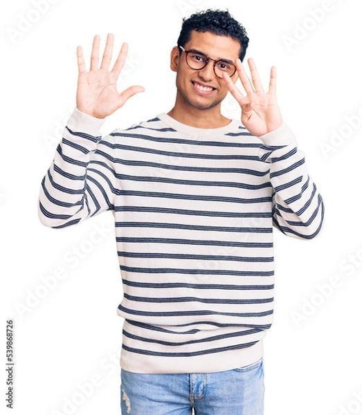 Fototapeta Hispanic handsome young man wearing casual clothes and glasses showing and pointing up with fingers number nine while smiling confident and happy.
