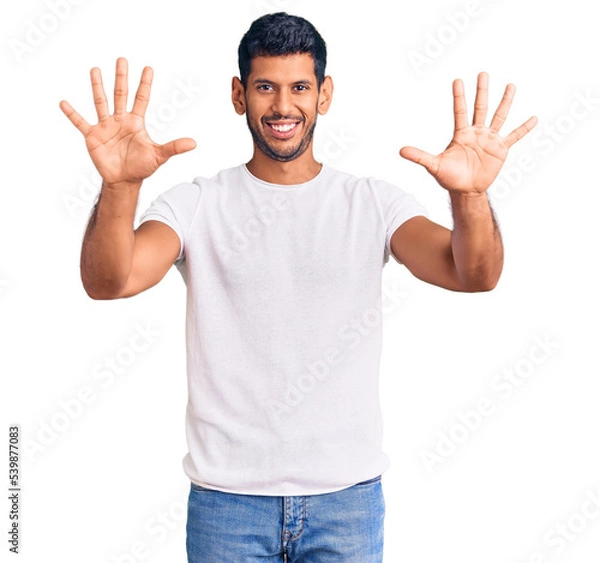 Fototapeta Young latin man wearing casual clothes showing and pointing up with fingers number ten while smiling confident and happy.