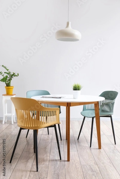 Fototapeta Dining table and chairs near white wall in room interior