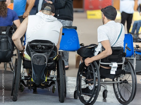 Fototapeta View from Behind of Two Boys Sitting in their Wheelchairs Watching other People
