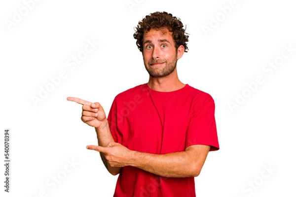 Fototapeta Young caucasian curly hair man isolated Young caucasian man with curly hair isolated shocked pointing with index fingers to a copy space.