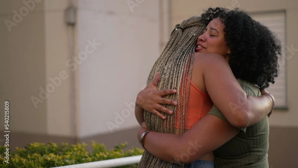 Fototapeta Female friend consoling desperate young woman. Two black sisters supporting each other. Friends embrace in crisis