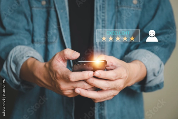 Fototapeta Selective focus at human hand while typing on laptop or smartphone to feedback on excellent customer service with five star score with smile. Service evaluation concept with futuristic icon.