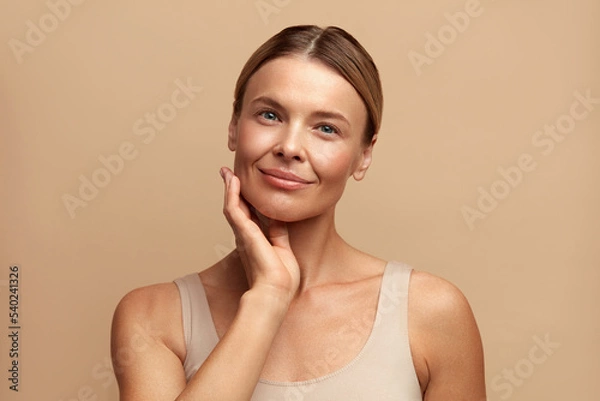 Obraz Smiling Woman Touching Face. Waist up Portrait of Attractive Woman Touching her Skin and Smiling. Woman Appearance and skin Care Concept 