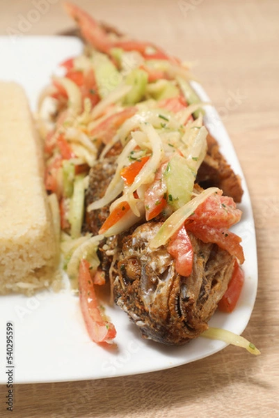 Fototapeta Delicious African dish featuring grilled fish with vegetables and a side of couscous served at a local restaurant