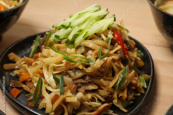 Fototapeta Nouilles Sautées au Bœuf et Légumes (Lagman ou Lo Mein), garnies de Concombre et Ciboule