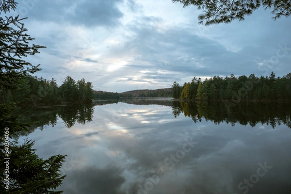 Fototapeta Clouds reflecting on a calm, tree lined lake. Maple Leaf Lake, Algonquin Provincial Park, Ontario, Canada.