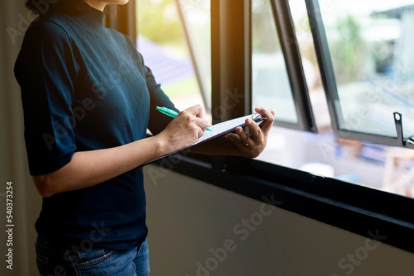Obraz Women home inspection surveyor and writing note on clipboard at a new property