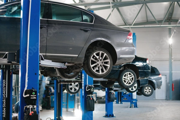 Fototapeta cars raised on car lifts located in the workshop of a car service