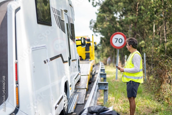 Fototapeta Caucasian man waiting tow truck motor home on the highway with a reflective vest and checking the vehicle