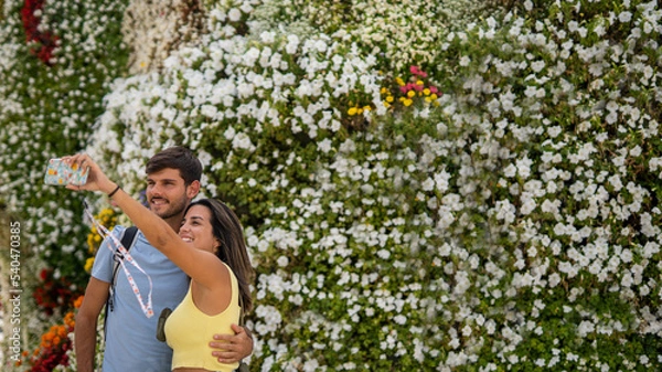 Fototapeta A young happy caucasian couple taking a photo in front of the Puppy sculpture in Bilbao