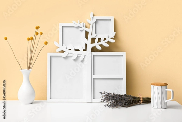 Fototapeta Family tree with photo frames, cup and flowers on table near yellow wall