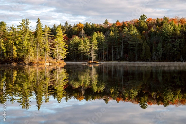 Fototapeta Islands and trees reflecting with clouds on a calm lake in the morning. Pincher Lake, Algonquin Provincial Park, Ontario, Canada.