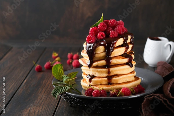 Obraz Pancakes. Pancakes with fresh raspberry with chocolate glaze or toppings in gray bowl on old wooden table background. Homemade classic american pancakes. Page for magazine concept.