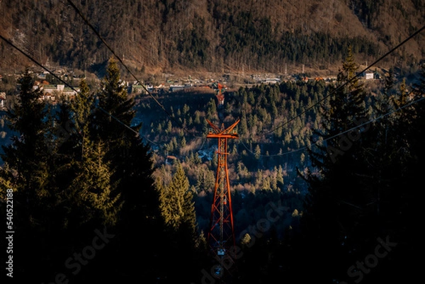 Fototapeta Panoramic view over the ski slope Poiana Brasov ski resort in Transylvania, Pine forest covered in snow on winter season,Mountain landscape in winter with the Bucegi Mountains in the background.