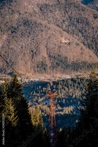 Fototapeta Panoramic view over the ski slope Poiana Brasov ski resort in Transylvania, Pine forest covered in snow on winter season,Mountain landscape in winter with the Bucegi Mountains in the background.