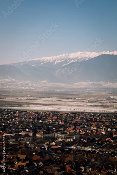 Fototapeta Panoramic view over the ski slope Poiana Brasov ski resort in Transylvania, Pine forest covered in snow on winter season,Mountain landscape in winter with the Bucegi Mountains in the background.