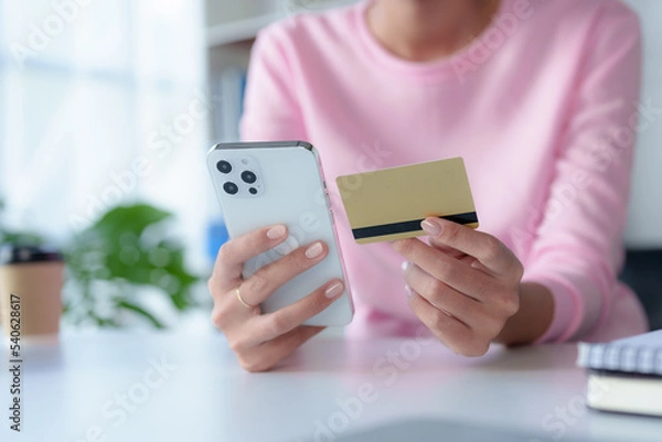 Obraz Close-up of woman enjoying the peace of mind of online shopping on mobile using credit card at home.