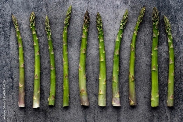Fototapeta Green fresh raw asparagus on concrete background.Bunch of fresh asparagus top view on gray concrete background